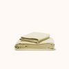 A folded organic matte sateen Límon sheet set on a white background, presented in a neat, organized stack.