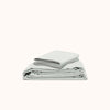 A neatly folded sheet set of organic matte sateen in Mist against a white background 