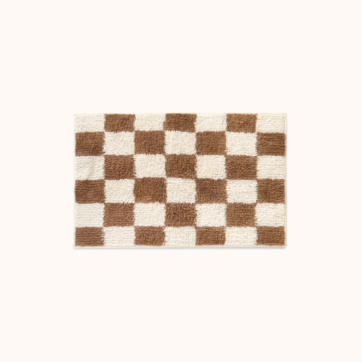 A rectangular plush bath mat with a brown and cream checkerboard pattern, centered on a solid off-white background.
