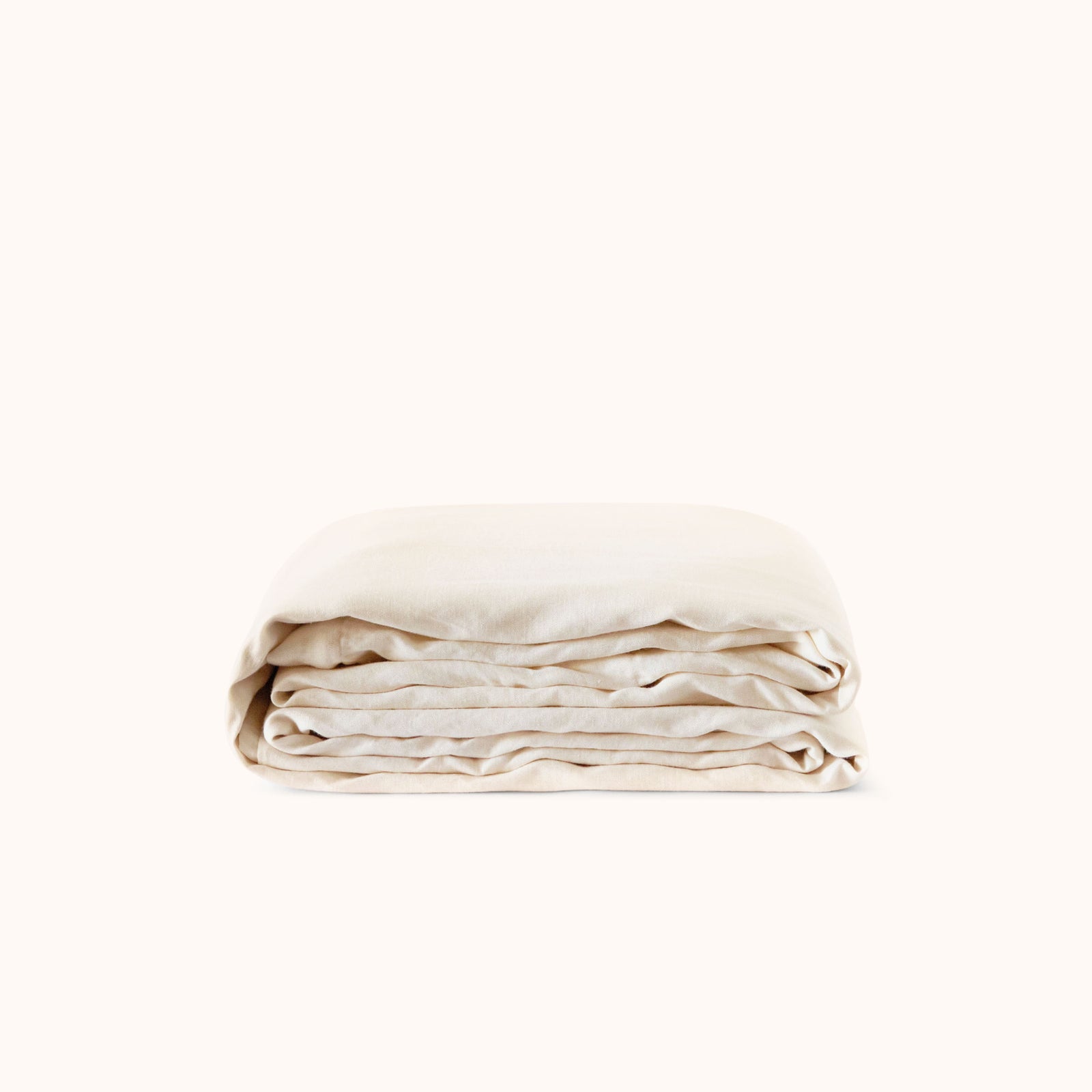 A folded cream colored duvet cover against a white background