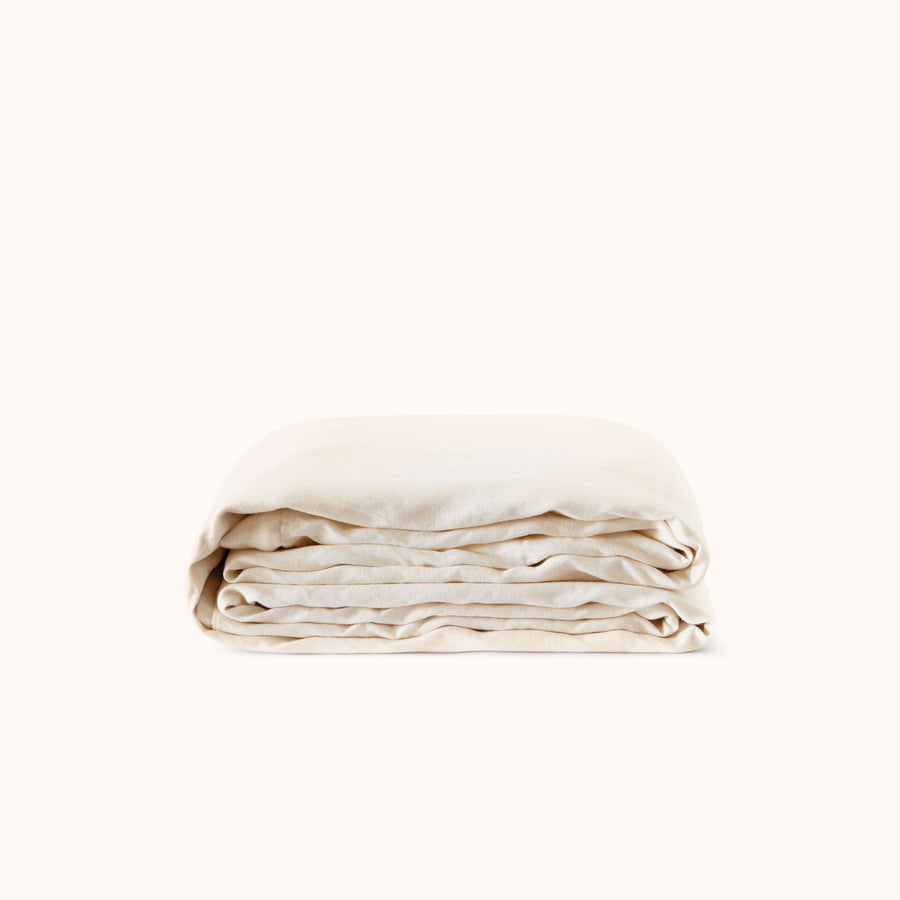A folded cream colored duvet cover against a white background