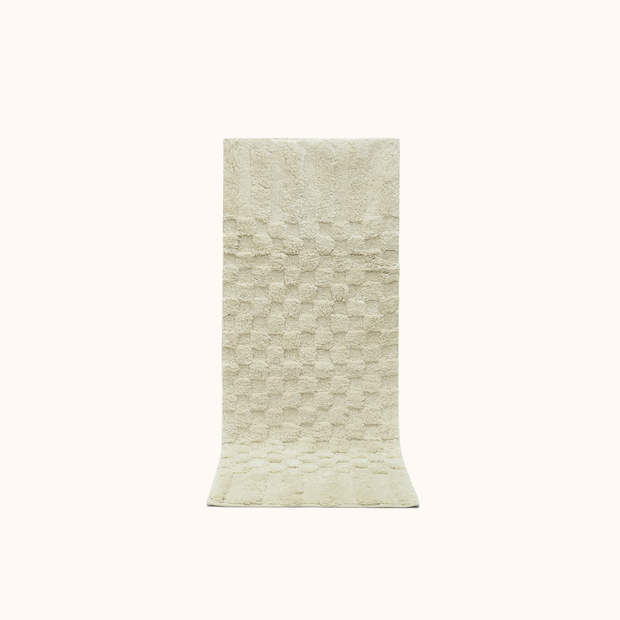A rectangular sage green bath runner with a subtle check pattern and contrasting shag heights.