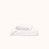 A folded white organic matte sateen sheet set on displayed against a white background.